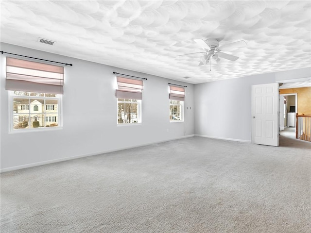 unfurnished room with visible vents, baseboards, ceiling fan, carpet floors, and a textured ceiling