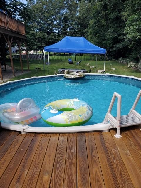 outdoor pool with a deck, a yard, and a fenced backyard