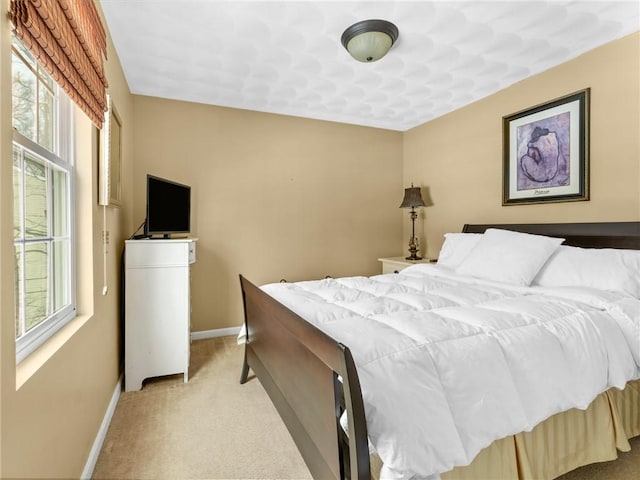 bedroom featuring baseboards and light carpet