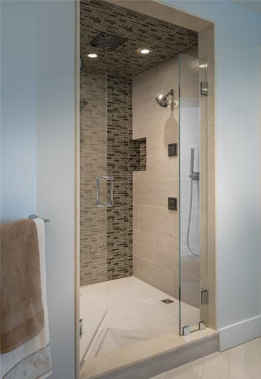 bathroom with tile patterned flooring, a shower stall, and baseboards