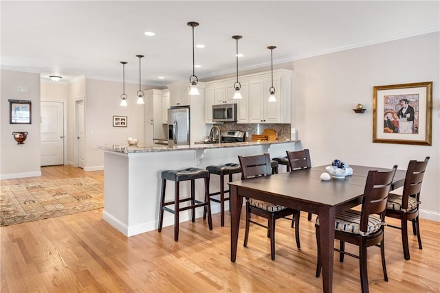 dining space with light wood finished floors, baseboards, ornamental molding, and recessed lighting