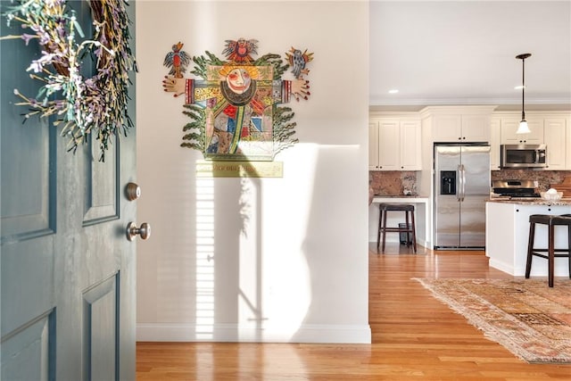 entryway featuring baseboards, crown molding, and light wood finished floors