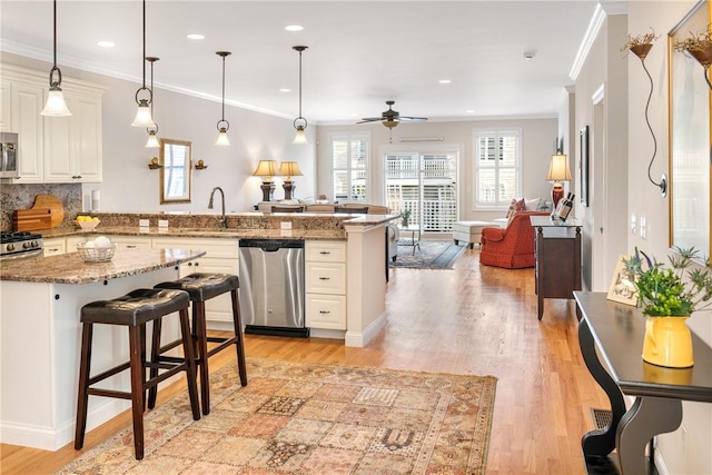 kitchen featuring stone countertops, appliances with stainless steel finishes, open floor plan, a kitchen breakfast bar, and hanging light fixtures