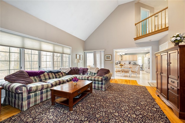 living room with high vaulted ceiling and light wood finished floors