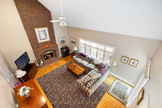 living room featuring high vaulted ceiling, a fireplace, wood finished floors, and a ceiling fan