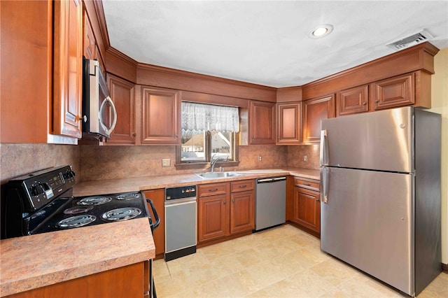 kitchen featuring light countertops, visible vents, appliances with stainless steel finishes, brown cabinetry, and a sink