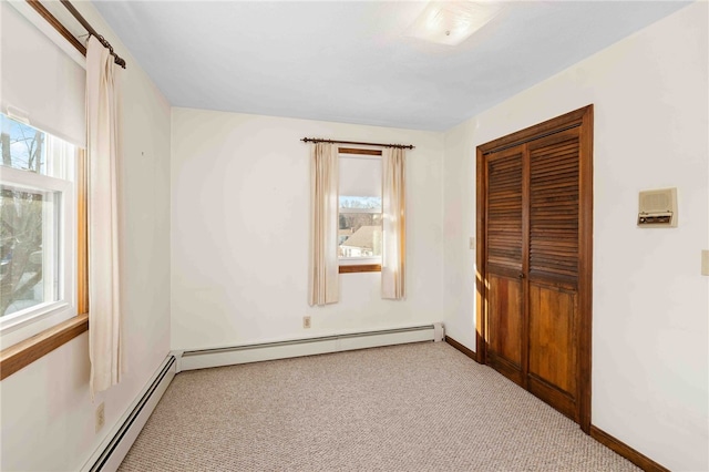 unfurnished bedroom with a baseboard radiator, multiple windows, and light colored carpet