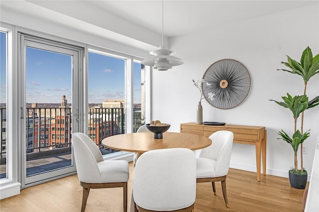 dining area featuring a view of city, light wood-type flooring, and baseboards