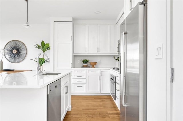 kitchen with light countertops, appliances with stainless steel finishes, hanging light fixtures, and white cabinetry