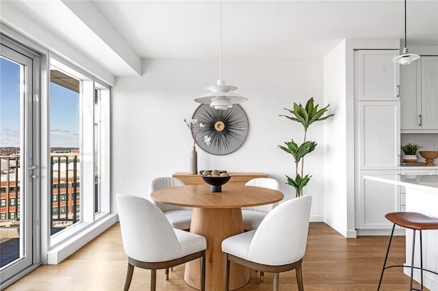 dining area with light wood-type flooring and baseboards