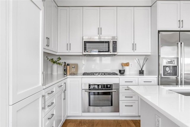 kitchen with light countertops, appliances with stainless steel finishes, wood finished floors, and white cabinetry