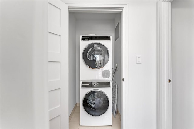 laundry area with laundry area, stacked washing maching and dryer, and light tile patterned floors