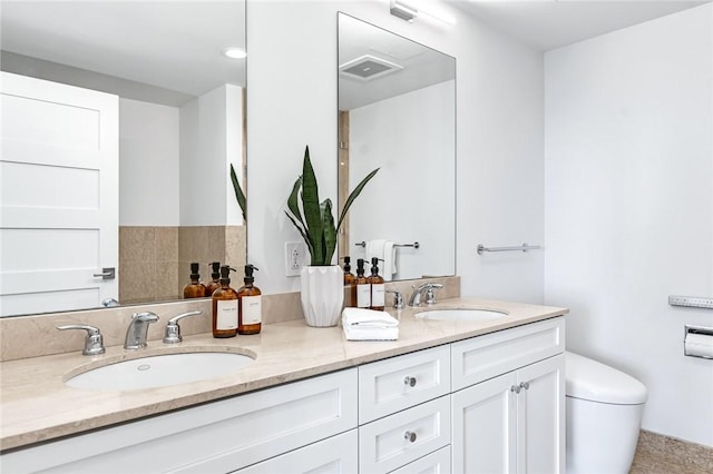 bathroom featuring visible vents, a sink, toilet, and double vanity