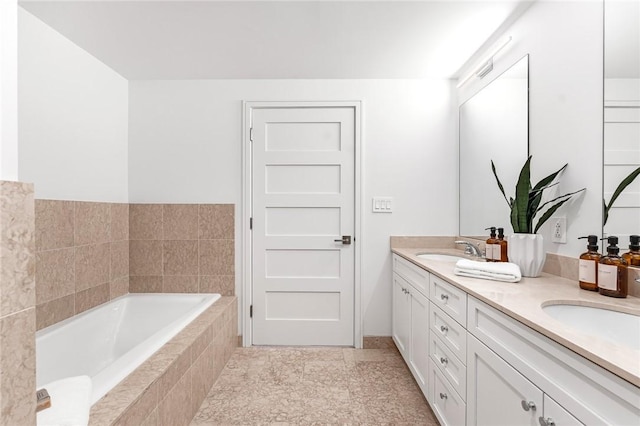 bathroom with double vanity, a relaxing tiled tub, and a sink