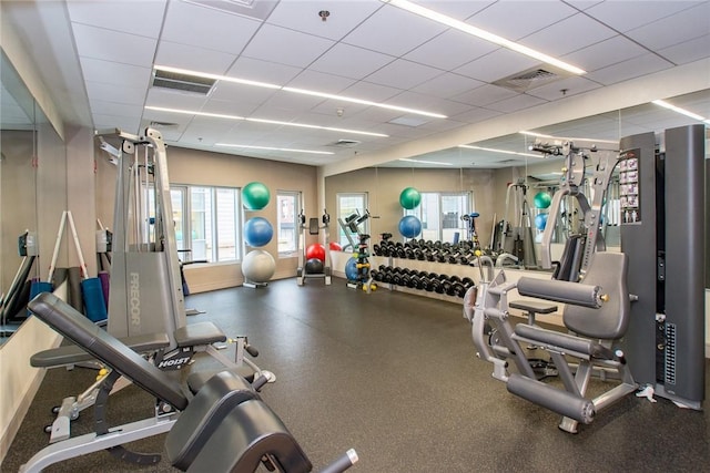 exercise room featuring baseboards, visible vents, and a drop ceiling