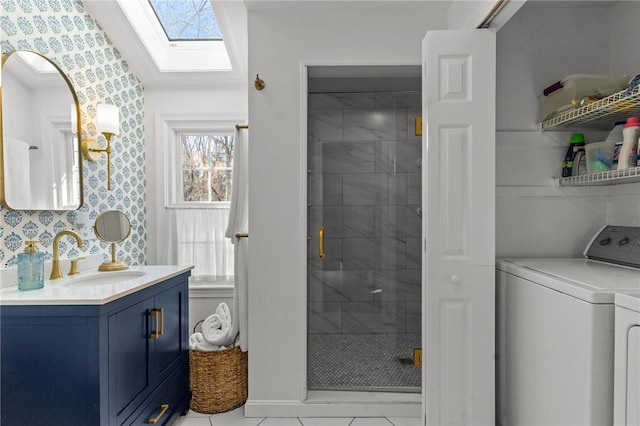 bathroom featuring a skylight, washer and clothes dryer, a stall shower, vanity, and wallpapered walls