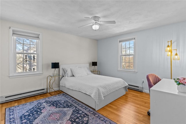 bedroom featuring ceiling fan, baseboard heating, and wood finished floors