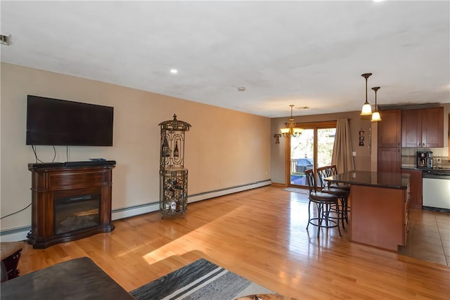 kitchen featuring a baseboard heating unit, a kitchen breakfast bar, dishwasher, light wood finished floors, and dark countertops