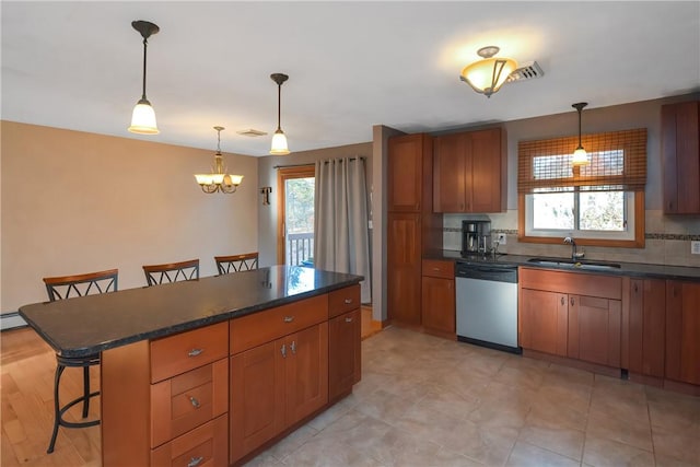 kitchen featuring dark countertops, a sink, a breakfast bar, and dishwasher