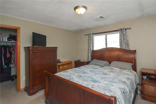 bedroom featuring light carpet, a closet, a walk in closet, and visible vents