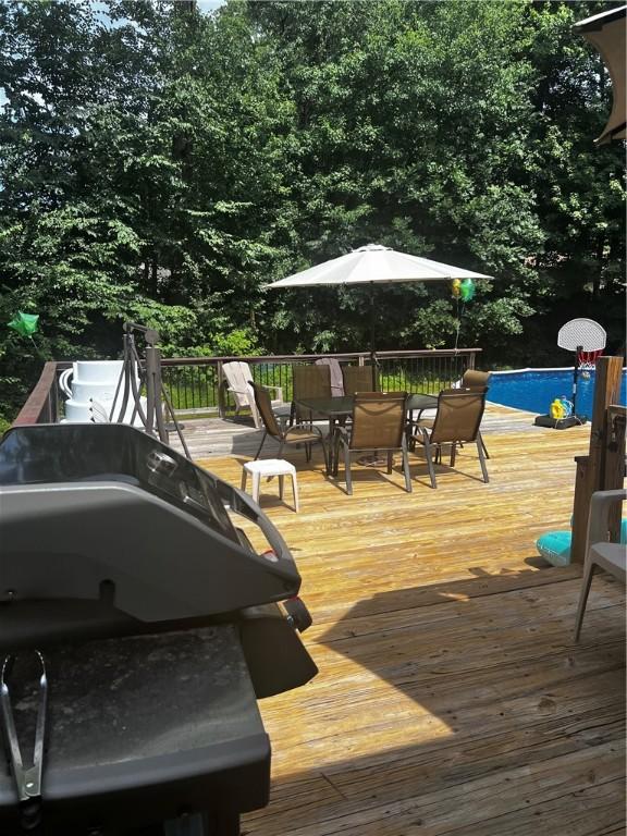 wooden terrace with outdoor dining space and an outdoor pool