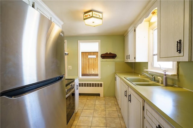 kitchen featuring a sink, white cabinetry, light countertops, appliances with stainless steel finishes, and radiator heating unit