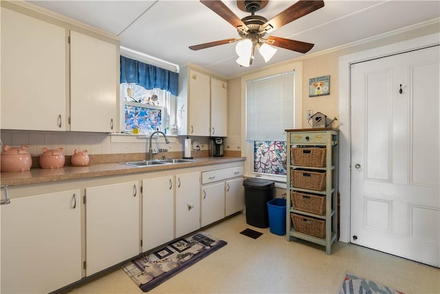 kitchen with light floors, light countertops, a ceiling fan, white cabinetry, and a sink