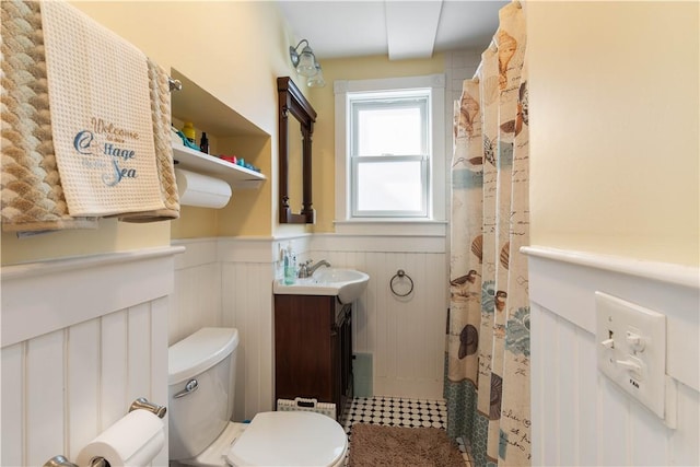 full bath with a wainscoted wall, vanity, and toilet