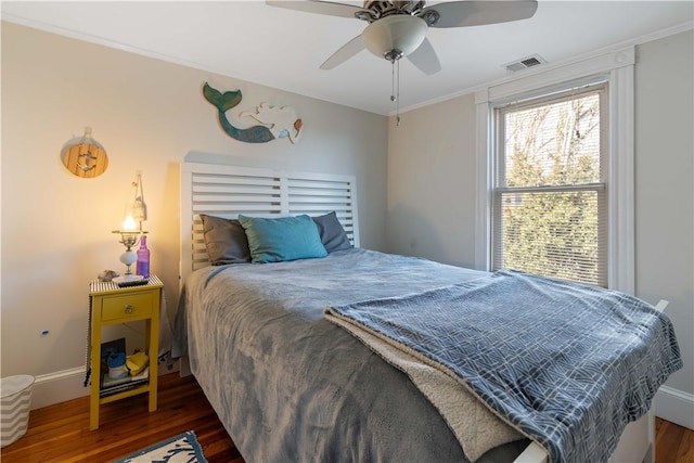 bedroom with visible vents, dark wood-type flooring, ornamental molding, a ceiling fan, and baseboards