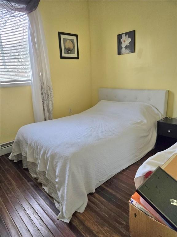 bedroom featuring baseboard heating and dark wood finished floors