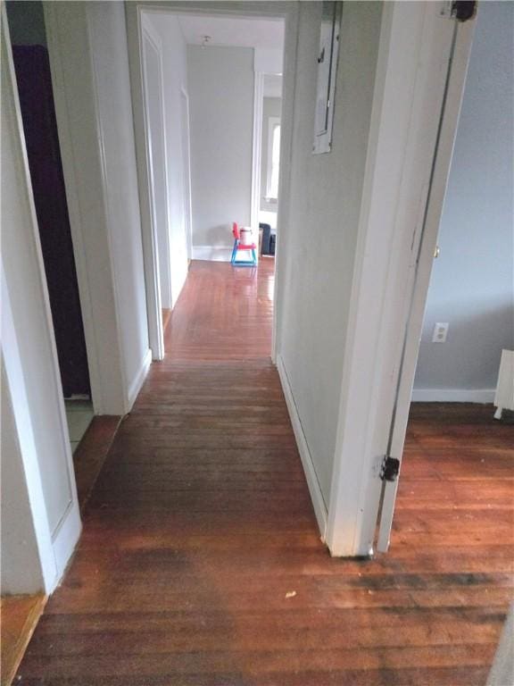 hall featuring dark wood-type flooring and baseboards