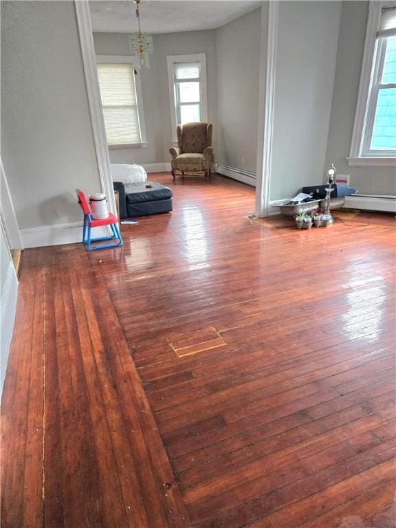 unfurnished room featuring a baseboard radiator, baseboards, and wood finished floors