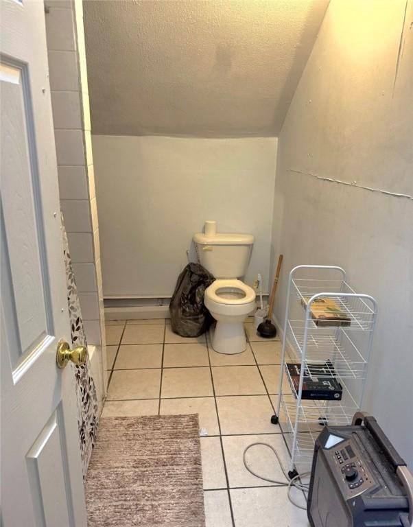 bathroom with toilet, tile patterned flooring, vaulted ceiling, and a textured ceiling