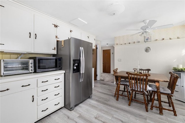 kitchen with a toaster, light countertops, light wood-style flooring, appliances with stainless steel finishes, and white cabinetry