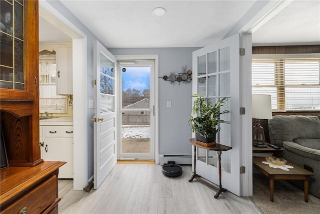 doorway to outside with light wood-style floors and baseboard heating