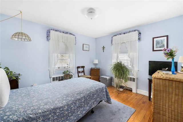 bedroom with baseboards, wood finished floors, and radiator