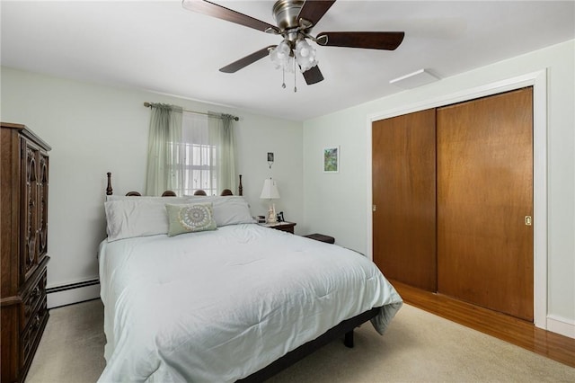 bedroom featuring light wood finished floors, a baseboard radiator, ceiling fan, and a closet