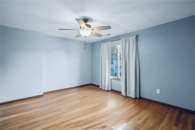 empty room with light wood-type flooring, visible vents, ceiling fan, and baseboards