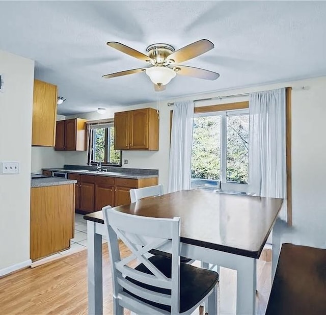 kitchen featuring a ceiling fan, baseboards, brown cabinets, a center island, and light wood finished floors