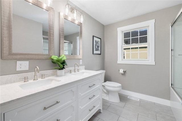 full bathroom with baseboards, a sink, toilet, and bath / shower combo with glass door