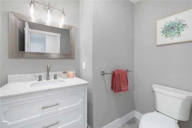 bathroom with toilet, vanity, and baseboards