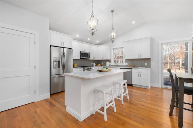 kitchen with light countertops, appliances with stainless steel finishes, a kitchen island, and white cabinets