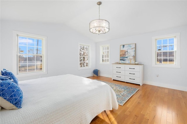 bedroom featuring lofted ceiling, light wood finished floors, baseboards, and an inviting chandelier