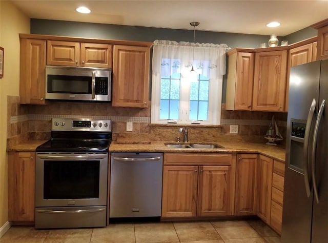 kitchen with a sink, appliances with stainless steel finishes, backsplash, light stone countertops, and decorative light fixtures