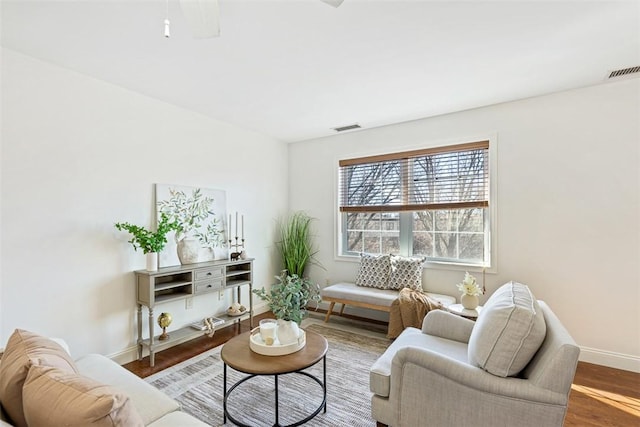 living room featuring visible vents, baseboards, and wood finished floors