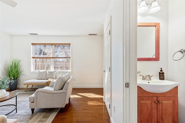 living room featuring visible vents, baseboards, and wood finished floors