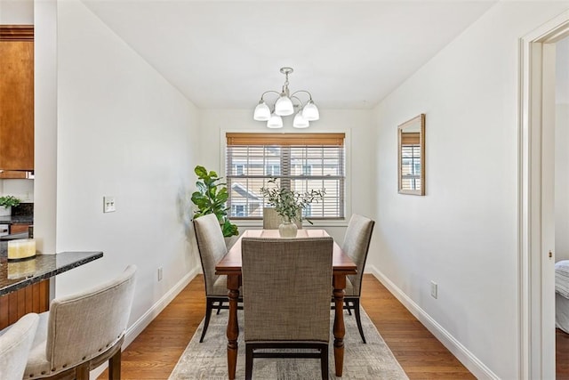 dining area featuring a notable chandelier, baseboards, and wood finished floors