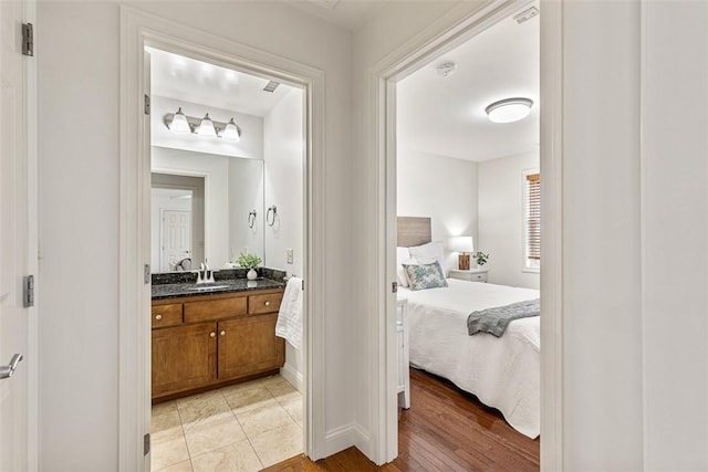 ensuite bathroom featuring vanity, ensuite bath, and wood finished floors