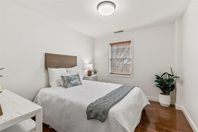 bedroom with wood finished floors, visible vents, and baseboards