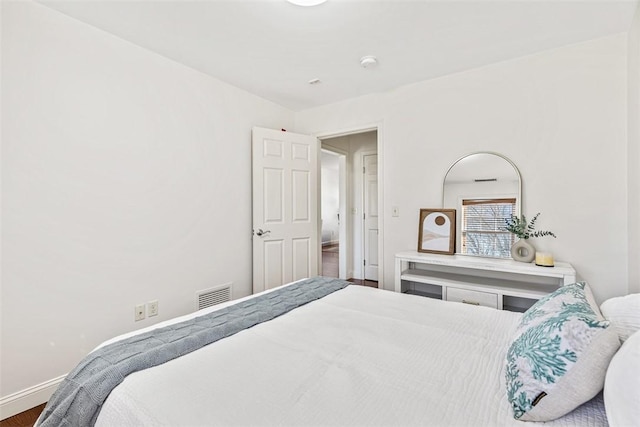 bedroom with visible vents, baseboards, and wood finished floors